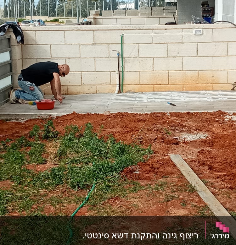 אדם עובד על ריצוף חצר עם כלים ודלי